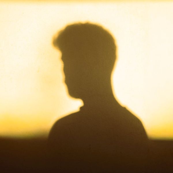 Silhouette of a person meditating with a calm expression, against a soft background.