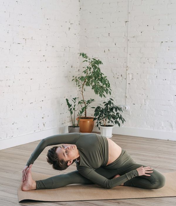 Woman performing a calm yoga pose in a dark room with lime green light accents.